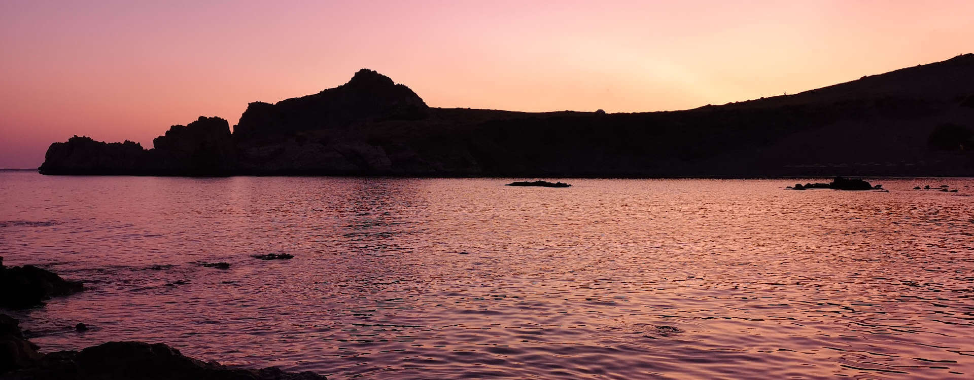 Sunset over the sleepy dragon rock at Agios Pavlos home of Yoga Rocks holidays