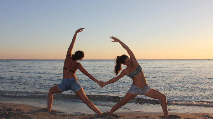 Yogis from Yoga Rocks retreat doing beach partner reverse warrior on the beach 