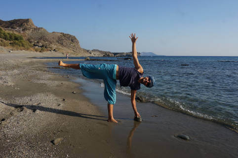 Ardha chandrasana on the wild beach with Sky coming to teach hatha yoga at Yoga Rocks Crete