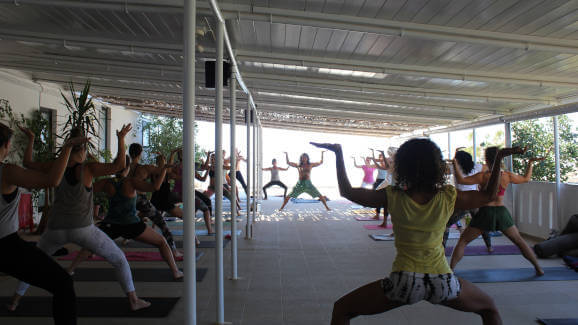 Danny Paradise teaching asana on Yoga Rocks terrace on Crete with Nadia assisting